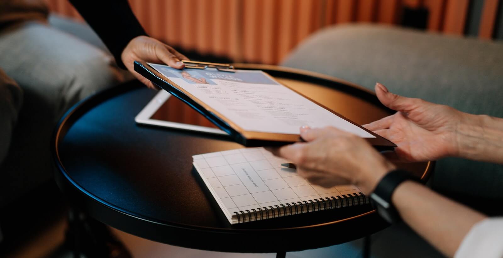 Two women passing a CV clipboard to each other during a job interview