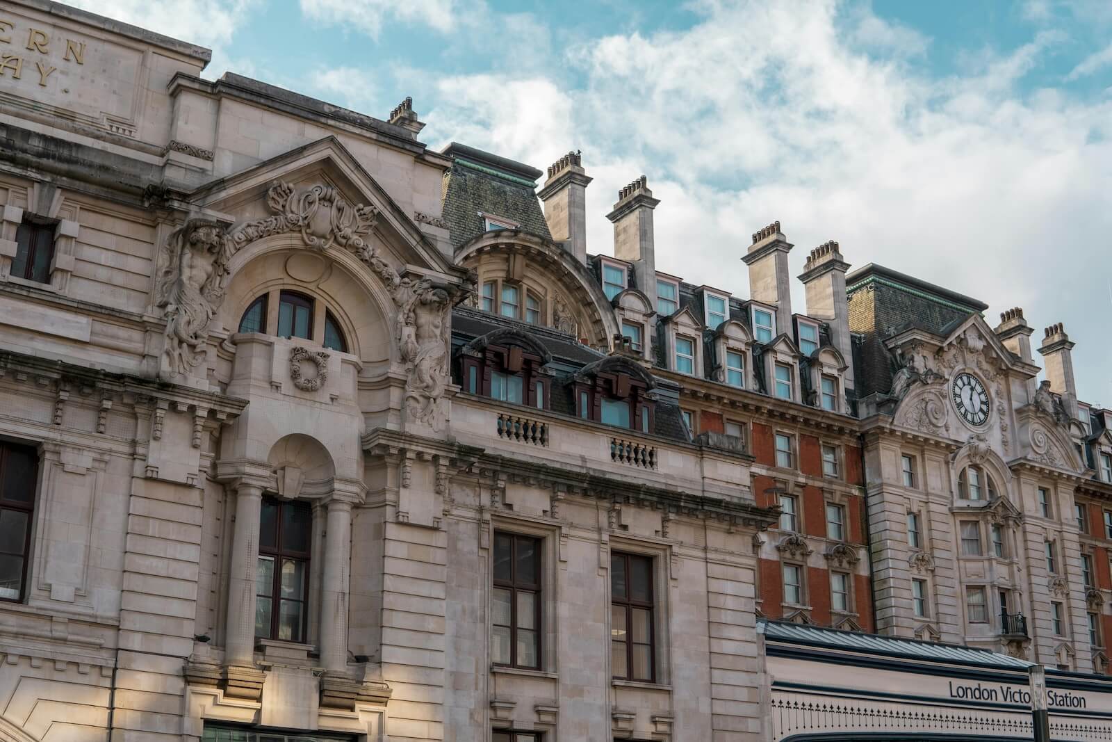 Historic London building facades against a blue cloudy sky